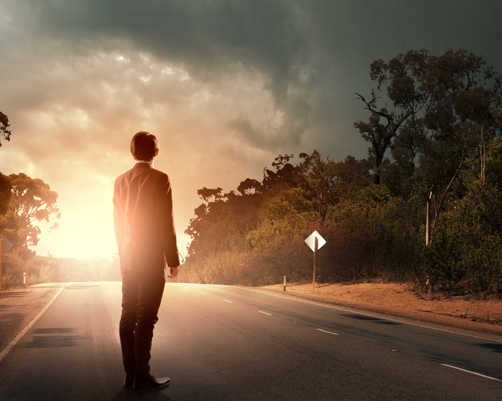 Back view of businessman standing on road and looking far away